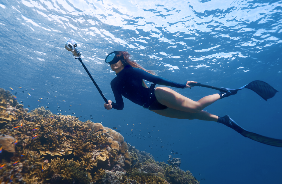 Snorkeler over reef with Insta360 on a selfie stick